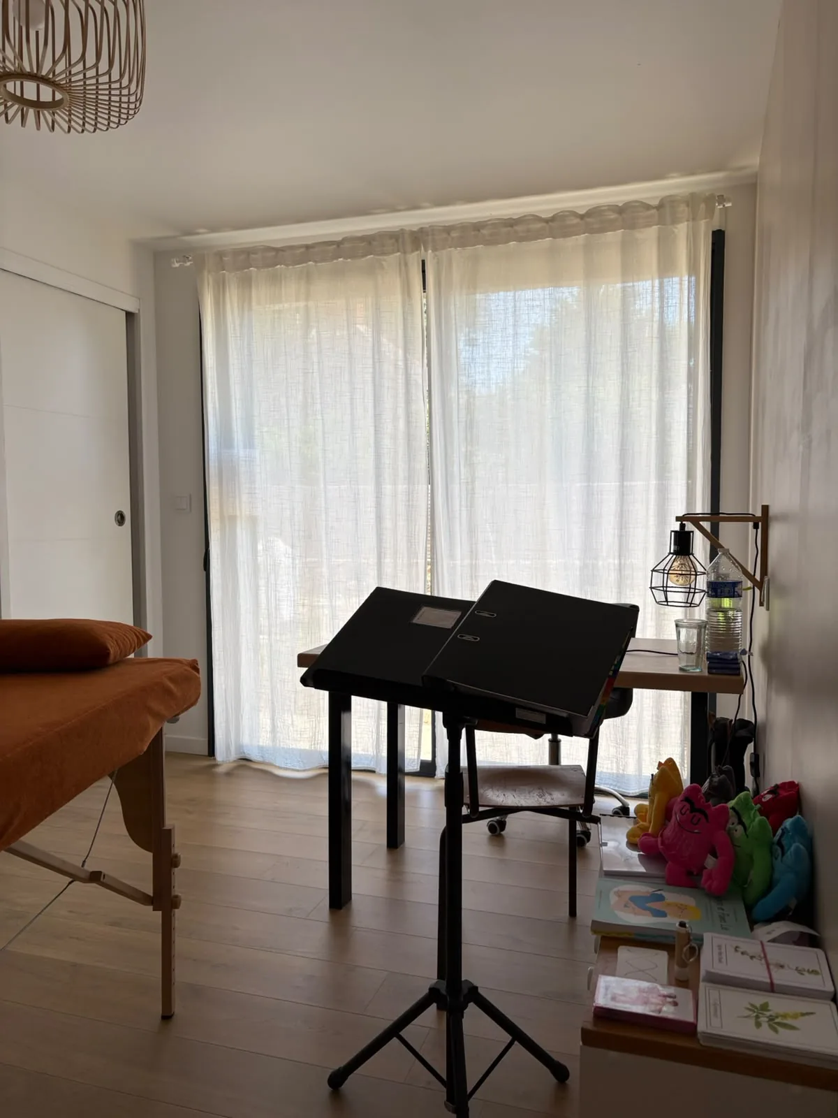 Vue du cabinet lumineux avec la table de massage et l’espace d’échange.