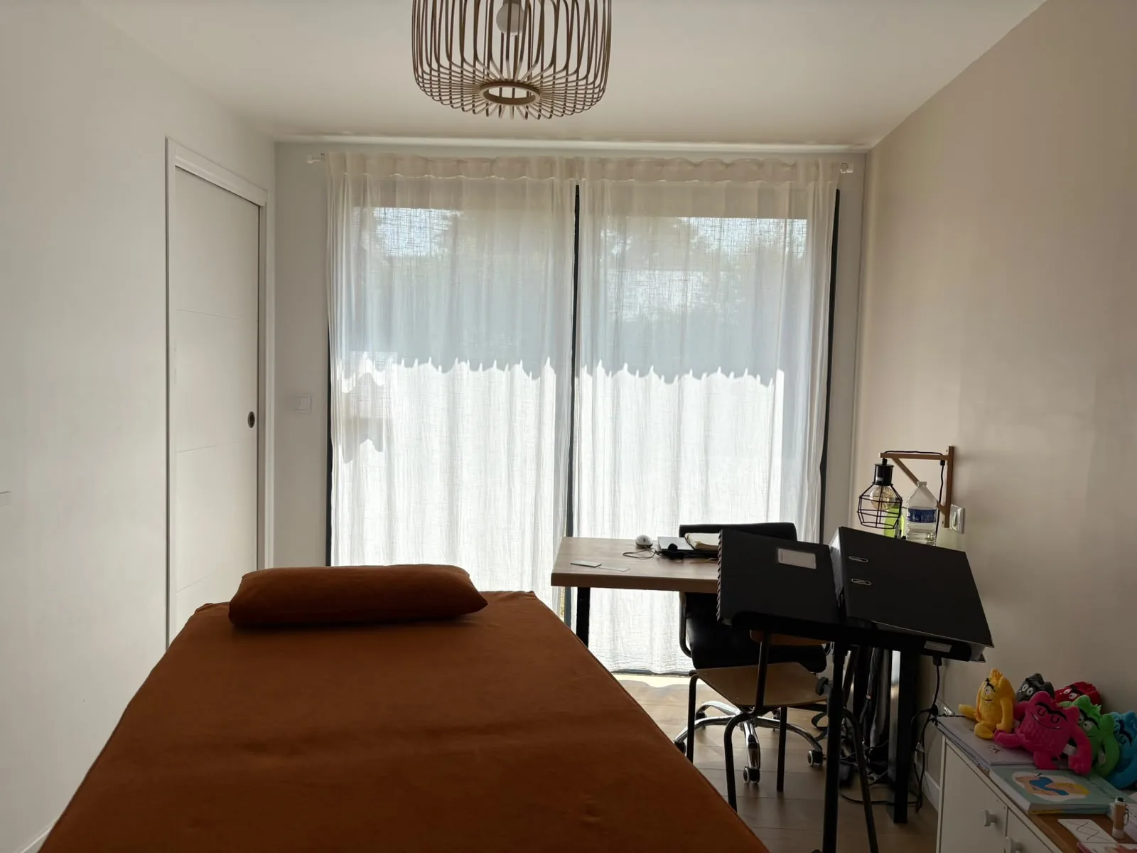 Le cabinet de kinésiologie avec la table de massage, le bureau et le support pédagogique.